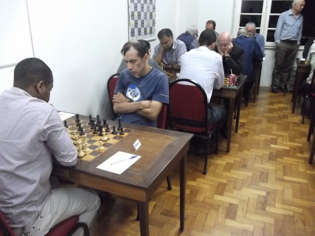 ALEX com carga máxima! Dez enxadristas jogando nas cinco mesas à esquerda! Ao fundo, Paschoal Mendes visitando o torneio