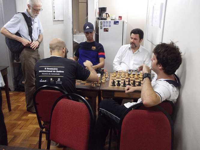 Antes do torneio começar, Sérgio Sundaus (em pé), Pádua e Léo observam uma partida Blitz entre André Kemper e Renato Werner (de costas)