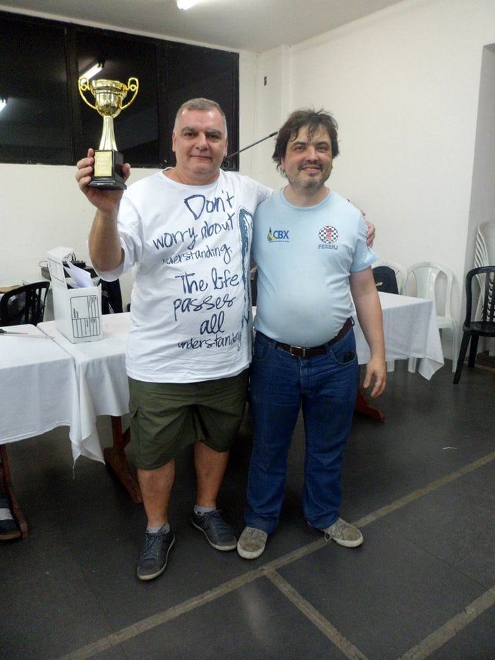 Márcio de Lucca Cardoso ergue seu troféu ao lado de Marcelo Einhorn
